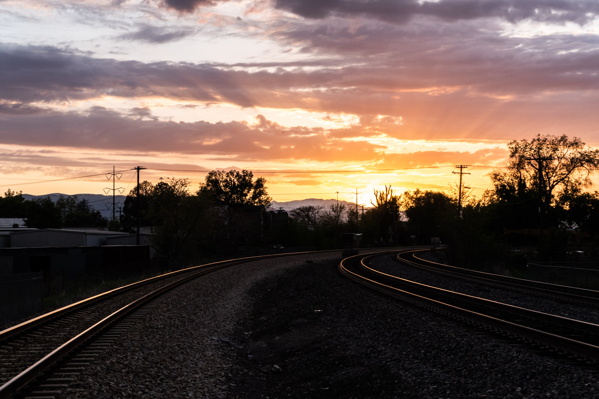 The sun sets lighting the train tracks orange